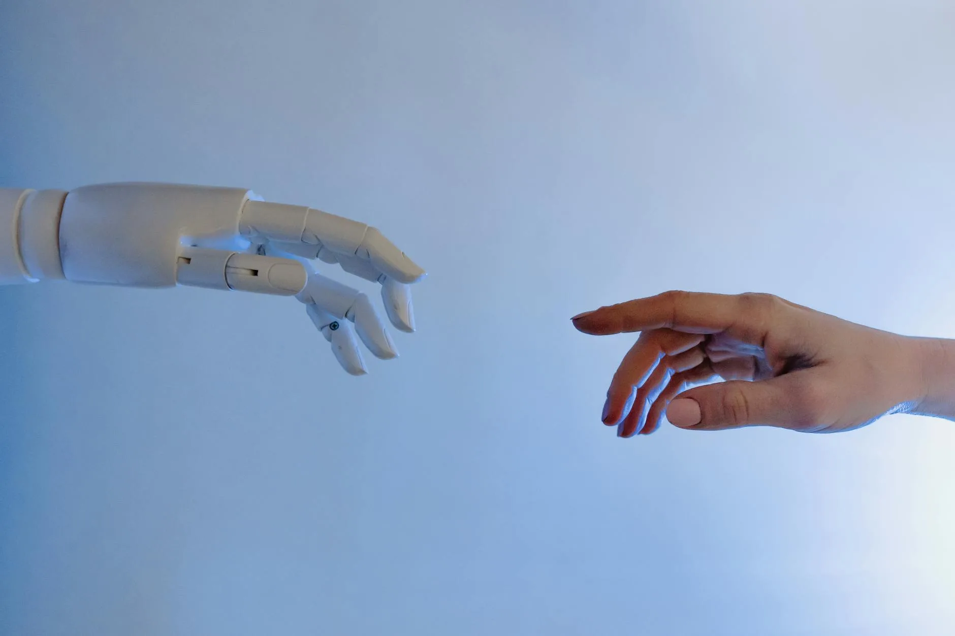 A human hand and a robotic hand reaching toward each other against a blurred office background